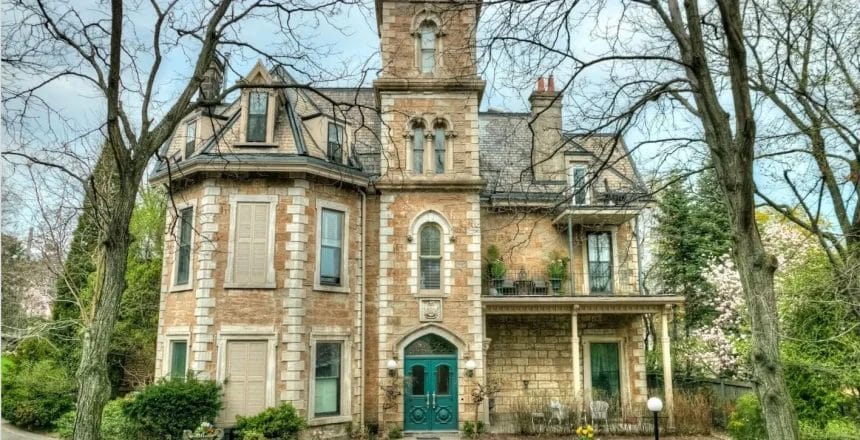 The historic Ballinahinch estate at 316 James Street South in Hamilton, Ontario, showcasing its 1850s stone architecture with a teal Gothic doorway, ornate marble mantle, and a private patio. This vintage condominium complex, renowned for its grand 12-foot ceilings and hardwood floors, captures the essence of Hamilton's architectural heritage.