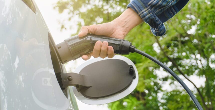 An electric vehicle is being charged at a station with lush greenery in the background, representing ElectricSafe's eco-friendly charging solutions in the GTA.